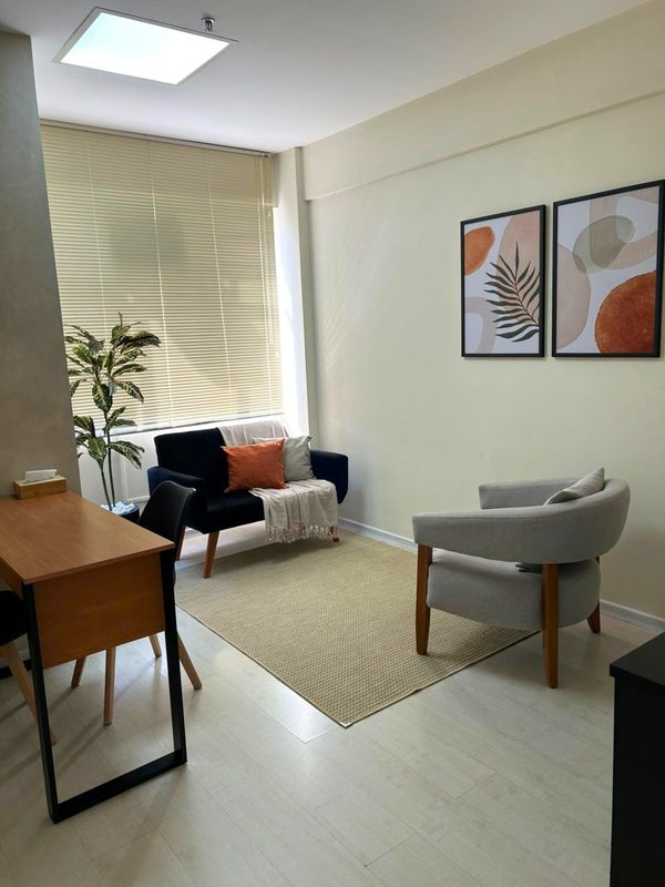 Sala de atendimento com poltrona, sofá e escrivaninha